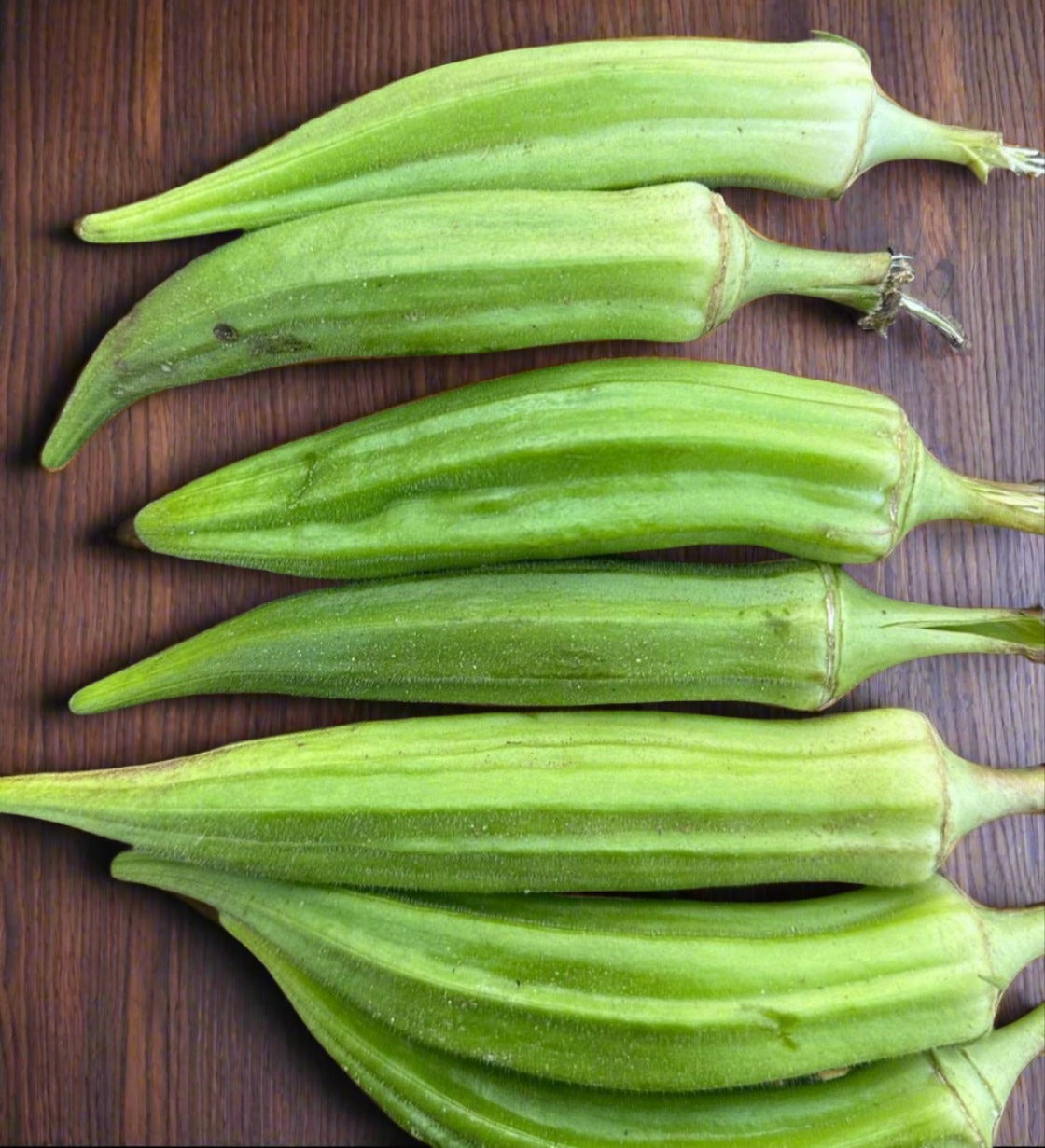 cut okra sitting on a wood grain table from seeds